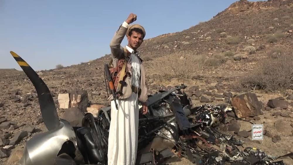 Houthi rebel beside drone wreckage